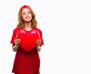 Young beautiful woman holding red heart in love over isolated background with a happy face standing and smiling with a confident smile showing teeth