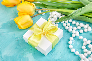 White gift box with yellow ribbon near yellow tulip