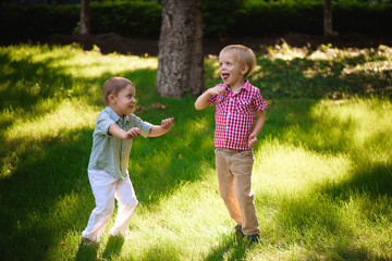 Fototapeta premium Two boys brothers playing and jumping outdoors in a park.
