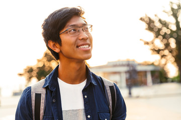 Picture of Cheerful asian male student in eyeglasses looking away