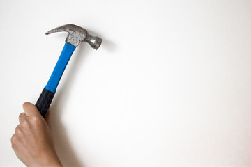 The hammer in the hand on the light backdrop