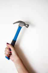 The hammer in the hand on the light backdrop