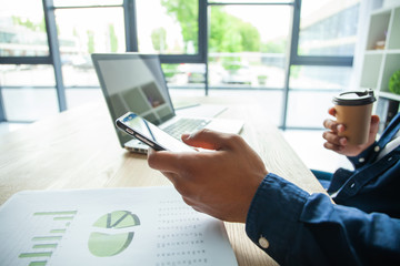 Happy african american businessman using a mobile phone in an office.