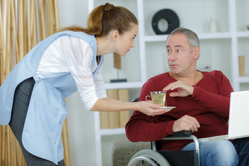 carer serving meal to man in wheelchair at home