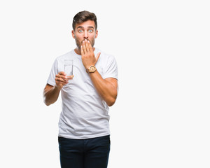 Young handsome man drinking glass of water over isolated background cover mouth with hand shocked with shame for mistake, expression of fear, scared in silence, secret concept