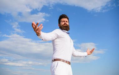 Fototapeta na wymiar Reached top. Hipster with beard and mustache looks attractive fashionable white shirt. Guy enjoy top achievement. Man bearded hipster formal clothes looks sharp sky background. Power and freedom