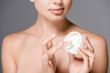 partial view of woman with face cream isolated on grey