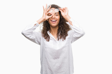 Beautiful young hispanic woman doing ok gesture with hand smiling, eye looking through fingers with happy face.