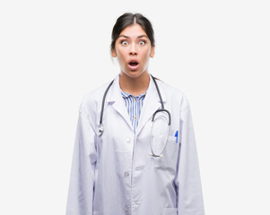 Fototapeta premium Young hispanic doctor woman scared in shock with a surprise face, afraid and excited with fear expression