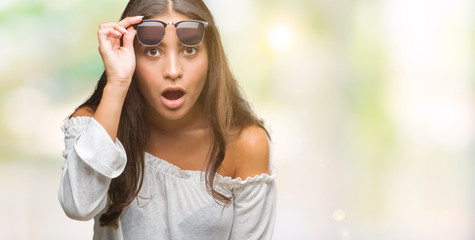 Young beautiful arab woman wearing sunglasses over isolated background afraid and shocked with...