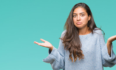 Young beautiful arab woman wearing winter sweater over isolated background clueless and confused expression with arms and hands raised. Doubt concept. - obrazy, fototapety, plakaty