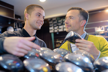 happy seller and customer reviewing clubs in golf store