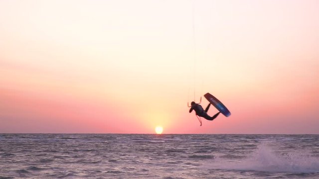 Performing stunts on kitesurf against the dawn of the sun