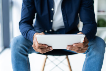 Hands of an African businessman using digital tablet in office.