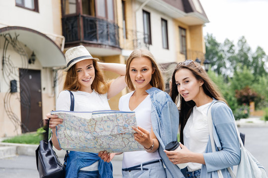 Beautiful woman traveler holding location map in hands in a city