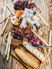 Different sorts of cheese and grapes on a wooden background. Vertical shot