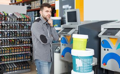 Man customer standing near technical computer in paint store