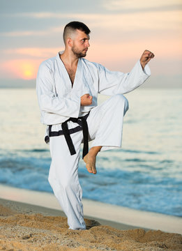 Young male doing karate at ocean quay