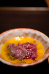 Tasty and delicious Sukiyaki Wagyu beef dipped in beaten whole raw fresh organic egg in Japanese style bowl. Traditional way to eat Japanese Sukiyaki. Rich with nutrient, benefit, protein and vitamin.