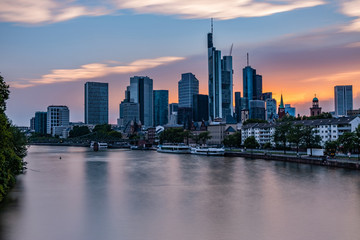 Obraz premium Frankfurter Skyline während des Sonnenuntergangs über dem Main, Blick auf das Bankenviertel - Sonnenuntergang mit roten und blauen Pastellfarben