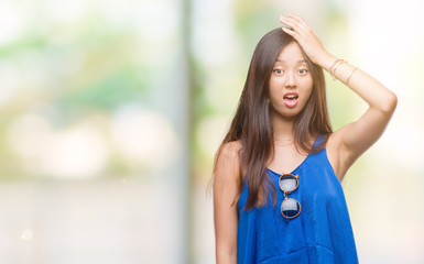 Young asian woman over isolated background surprised with hand on head for mistake, remember error....