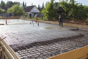 worker leveling fresh concrete slab with a special working tool