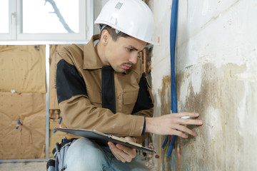 young worker checking the wall of a house