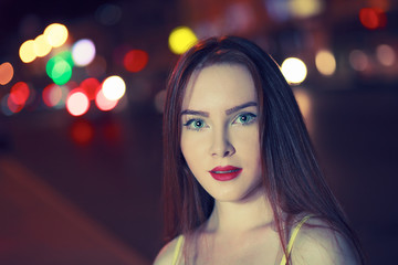 Gorgeous brunette girl portrait over night city defocused lights. Vogue fashion style portrait of young pretty female with long dark hair. Shallow DOF