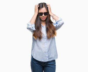 Young asian woman wearing sunglasses over isolated background suffering from headache desperate and stressed because pain and migraine. Hands on head.