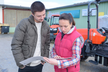 saleswoman convincing young famrer to buy new agricultural machinery