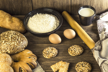 Food. Baking bread. Fresh bread baked in a bakery, biscuits, chicken eggs and flour on the background of a wooden table texture