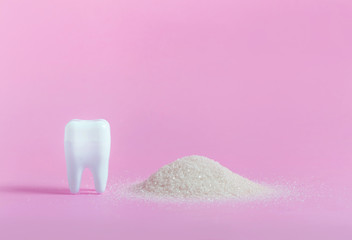 Plastic tooth and toothbrush in big pile of sugar.