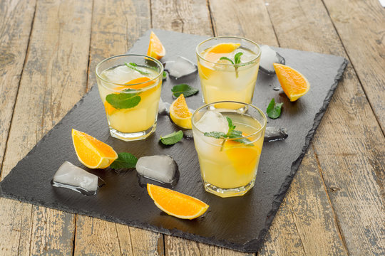 Cocktail. Orange juice with mint and ice on rustic wooden table