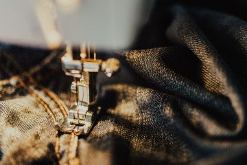 Repair jeans on the sewing machine. View of the fabric, needle and thread. Illumination from the...