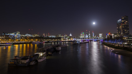 Fototapeta na wymiar The moon shining brightly over the City of London.