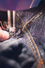 Repair jeans on the sewing machine. View of the fabric, needle and thread. Illumination from the...