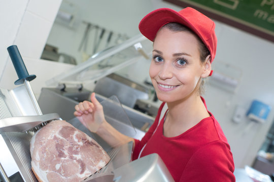 female butcher cutting meat on machine