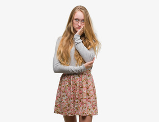 Blonde teenager woman wearing flowers skirt thinking looking tired and bored with depression problems with crossed arms.