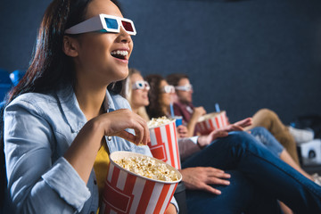 happy asian woman in 3d glasses with popcorn watching movie in cinema
