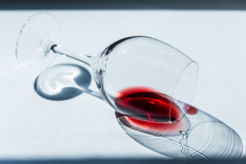 A sip of red wine in a wine glass, lying on the table in harsh sunlight.