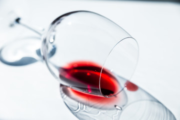 A sip of red wine in a wine glass, lying on the table in harsh sunlight.