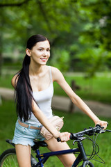 Fototapeta premium Teen girl with bicycle in a park.