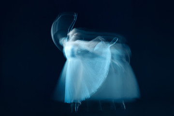 The photo as art - a sensual and emotional dance of beautiful ballerina through the veil on a dark background. A stroboscopic image of the one model