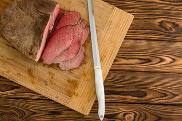 Overhead view of sliced meat next to knife