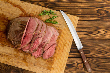 Steak sitting on cutting board next to knife