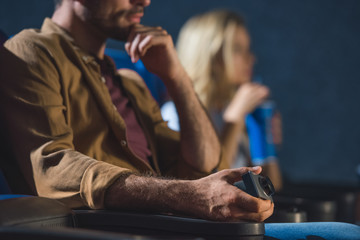 partial view of man with small video camera illegally filming movie in cinema
