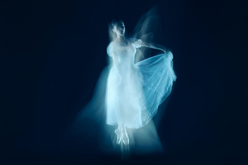 The photo as art - a sensual and emotional dance of beautiful ballerina through the veil on a dark background. A stroboscopic image of the one model