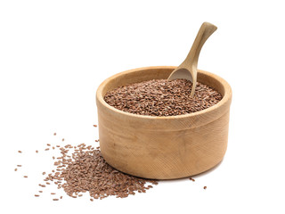 Linseeds or flax seeds in a wooden bowl and a spoon in it with small pile on the side seen from low angle and isolated on white background