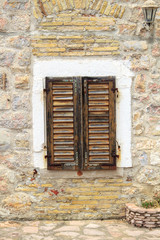 stone wall with closed wooden shutters window in Budva Old Town