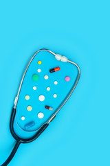 Stethoscope and different pills on blue background